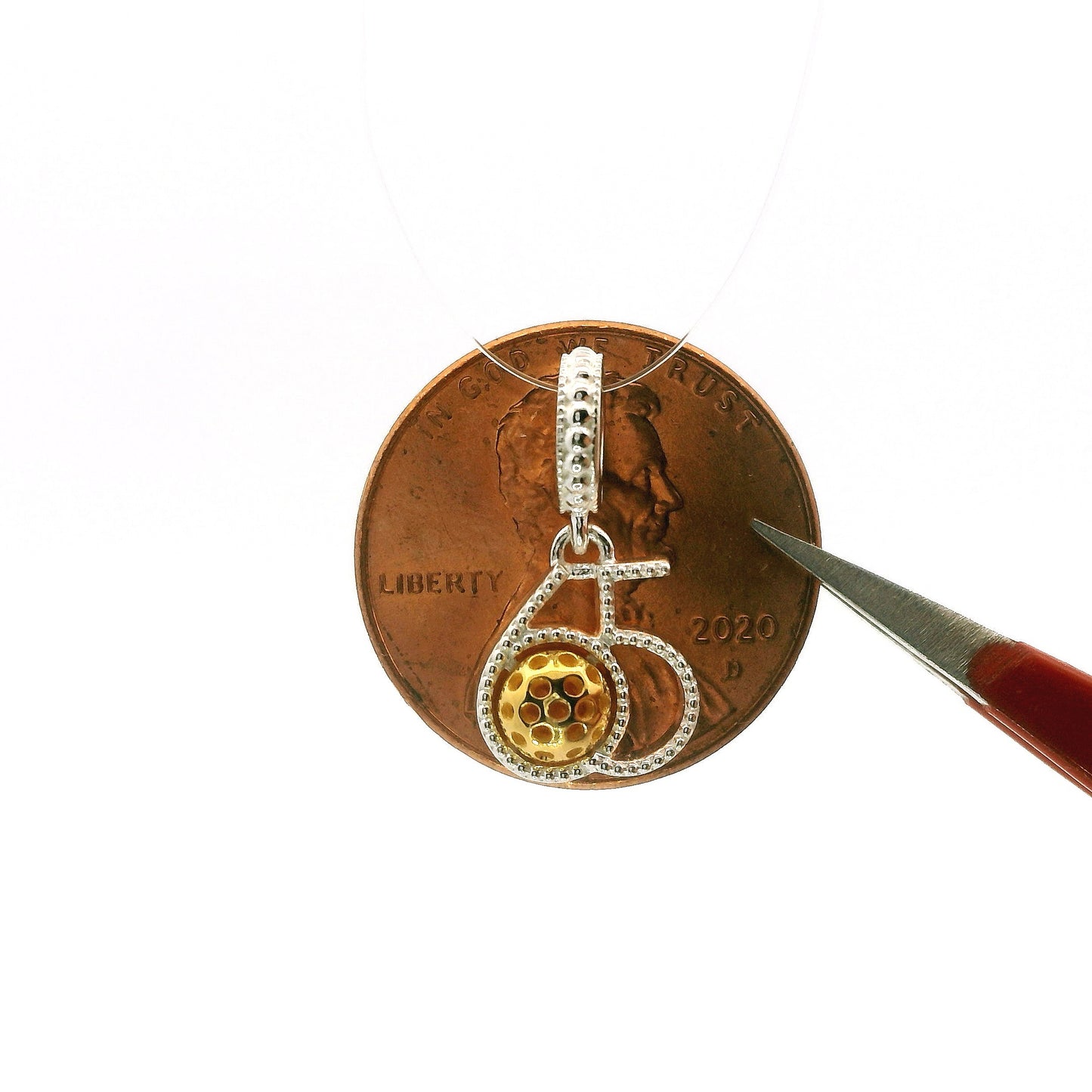 Small silver and gold pendant on a copper penny