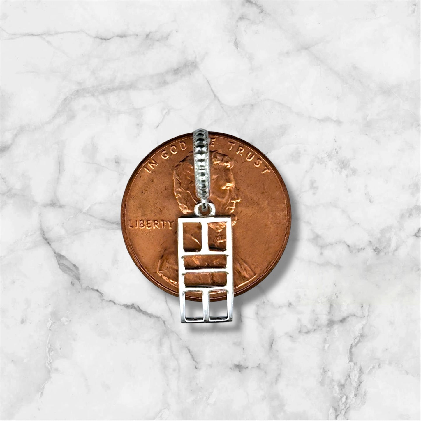 Silver pendant on a penny against a marble background