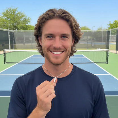 Man holding a pendant on a chain while standing on a pickleball court