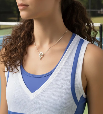Woman wearing a blue and white athletic top with a necklace featuring a paddle pendant.