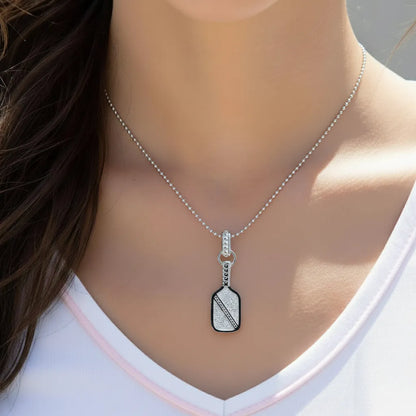 Silver necklace with a pickleball paddle pendant worn by a person