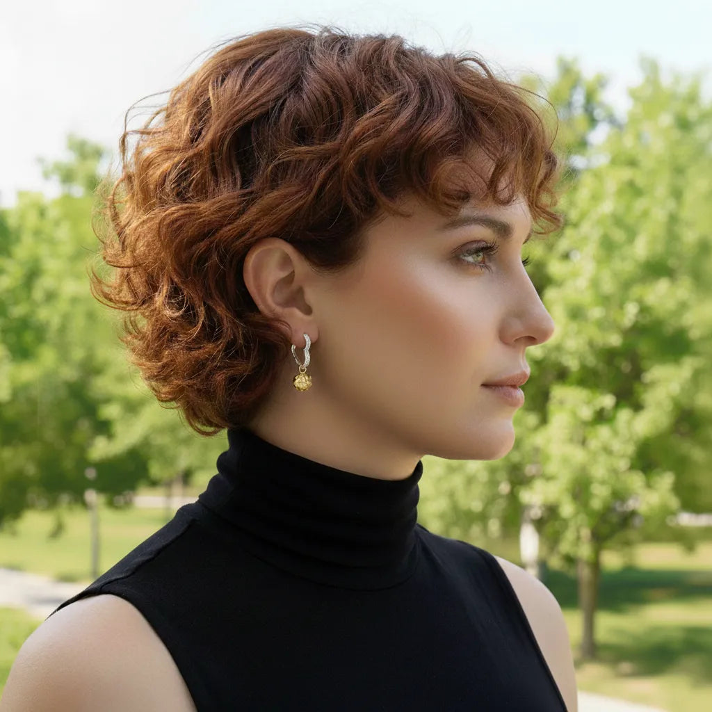 Woman with styled hair in an outdoor setting wearing a gold and silver earring.