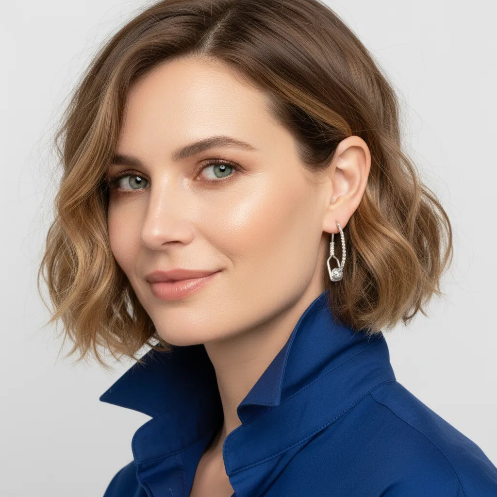 Woman with short brown hair wearing a blue top and silver earring against a light gray background