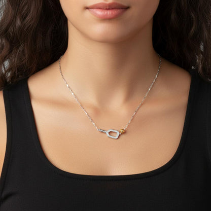 Necklace with a silver pickleball paddle and gold ball pendant worn by a person against a dark background.