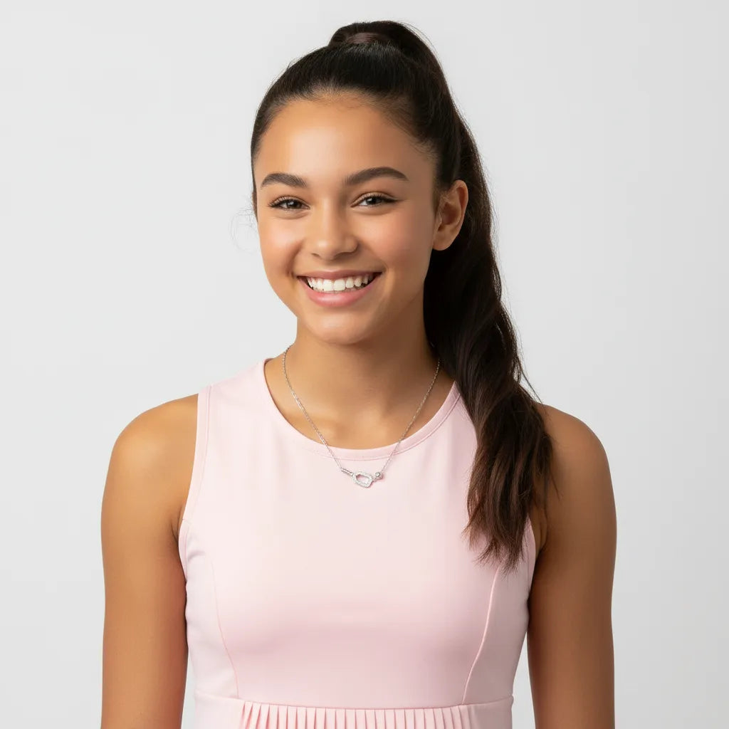 Female teenage kid wearing a pink dress and silver necklace against a light gray background