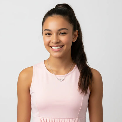 Female teenage kid wearing a pink dress and silver necklace against a light gray background