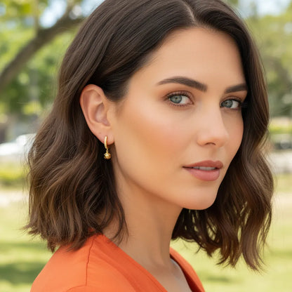 woman wearing gold pickleball earrings standing outside with blurred background
