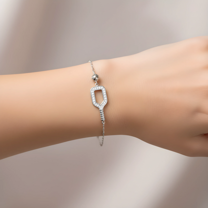 Silver pickleball paddle and ball bracelet worn on a wrist against a neutral background.