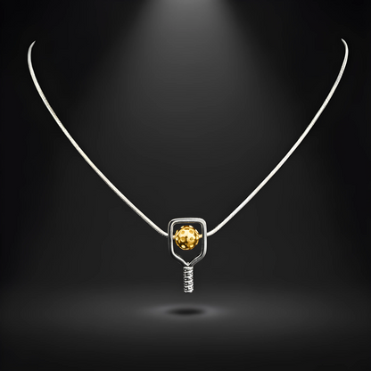 Necklace with a pendant featuring a silver paddle and a yellow pickleball on a dark background
