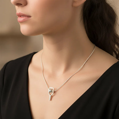 Woman wearing a silver necklace with a pendant against a neutral background